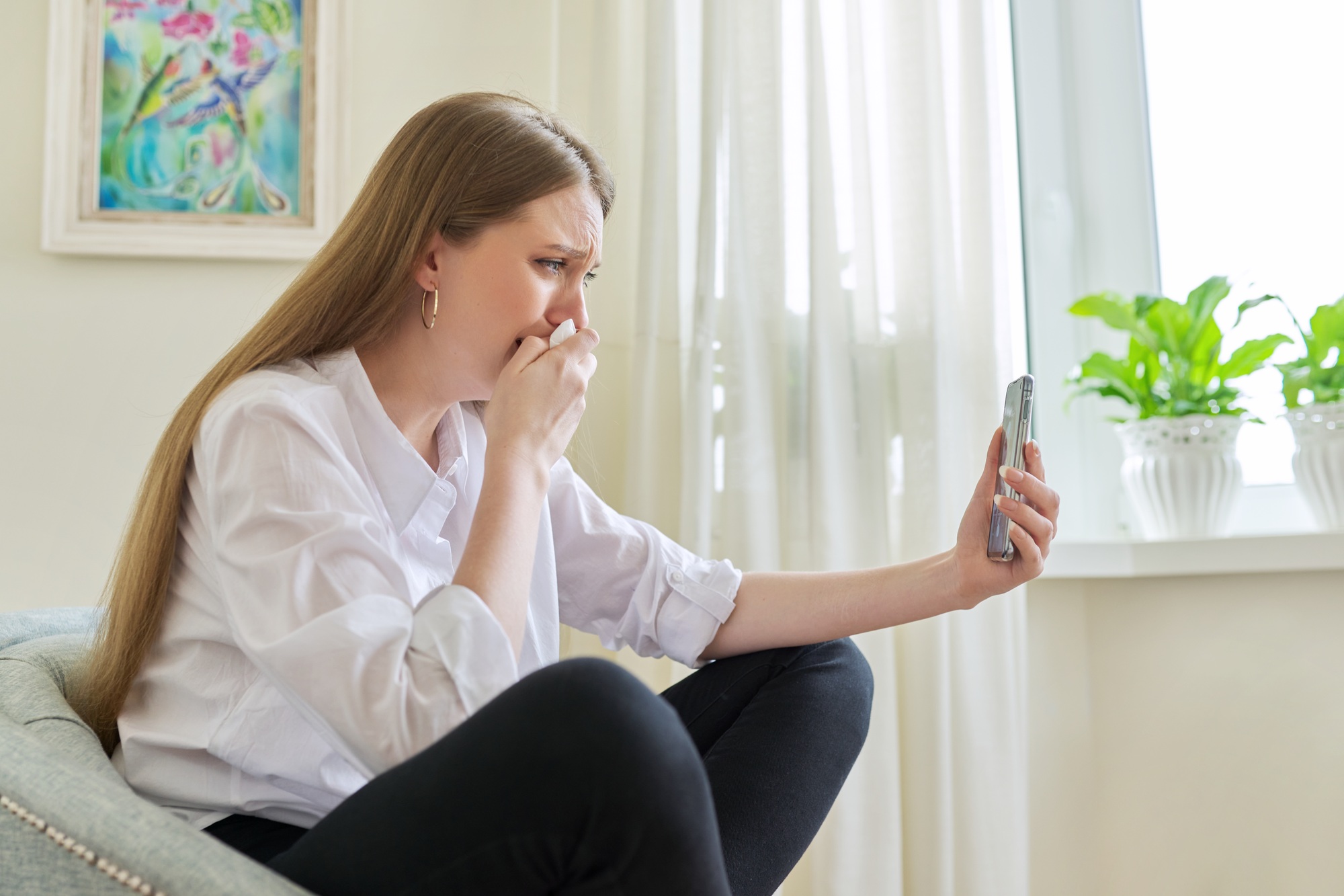 Young woman crying looking at smartphone screen